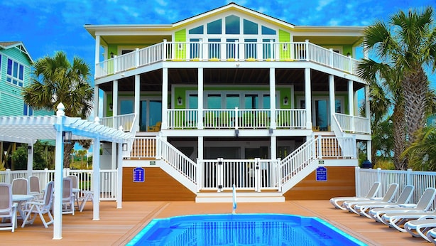 A multi-story hotel with a pool area, outdoor seating, and a balcony.
