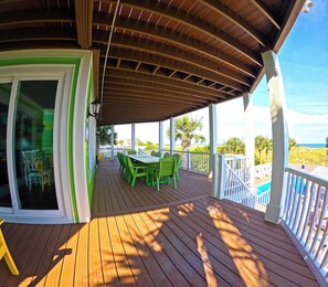 A wooden deck with a covered area, green outdoor furniture, and a view of the ocean. -  OCEAN FRONT HOME w/Heated private Pool, Elevator, 12 Bed/12 Bath, Pet Friendly (Holden Beach)