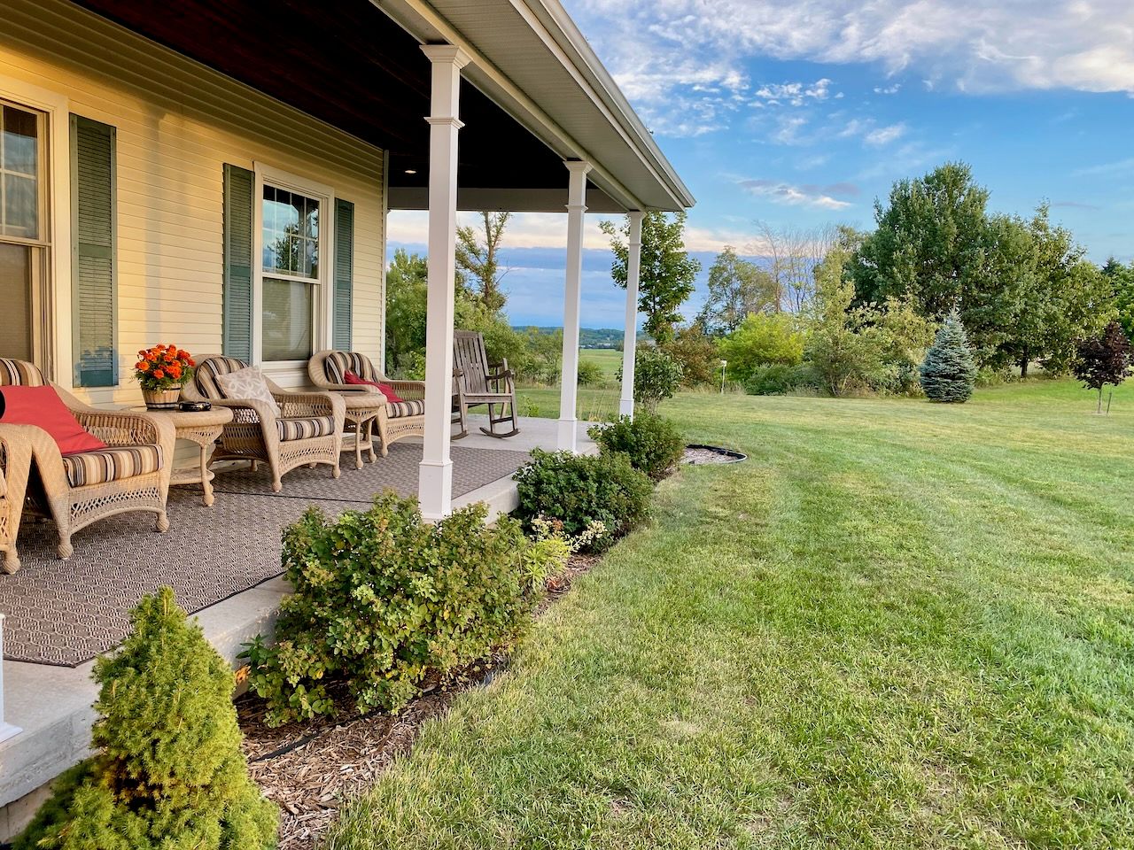 A covered porch with outdoor furniture and a well-maintained lawn.