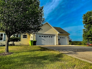 A two-story house with a garage, a lawn, and a tree in front.