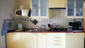 Uma cozinha compacta com micro-ondas, fogão, pia e armários.