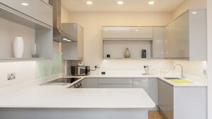 A modern kitchen with white cabinetry, a central island, a microwave, and a sink. - Beautiful 2 bed terrace flat close to Greenwich -  Pass the Keys (London)