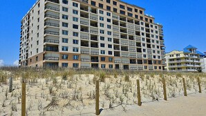 Un hotel de varios pisos con balcones, situado cerca de una zona de playa arenosa.