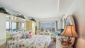 Un dormitorio con cama, cómoda, espejo, lámpara y ventana con vistas.