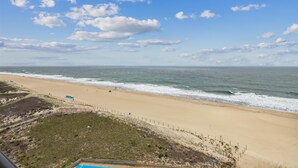 Una playa con arena, una cerca de madera y un cielo despejado con nubes.