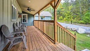 Eine überdachte Veranda mit Holzgeländern und Adirondack-Stühlen.