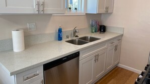 A kitchen with white cabinets, a double sink, and a dishwasher.