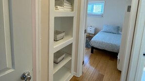 A bedroom with a bed, a nightstand, and a window with blinds.