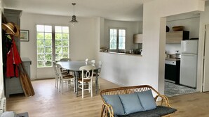 Ein geräumiger Wohnbereich mit Esstisch, Rattan-Sofa und einer Küchenzeile inklusive Kühlschrank und Spüle.