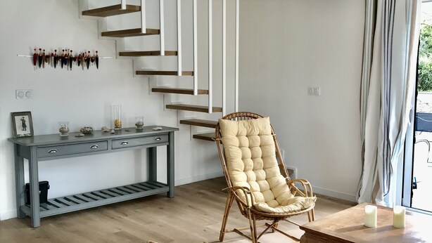 Ein modernes Interieur mit Treppe, Korbmöbeln und einer Konsolentisch.