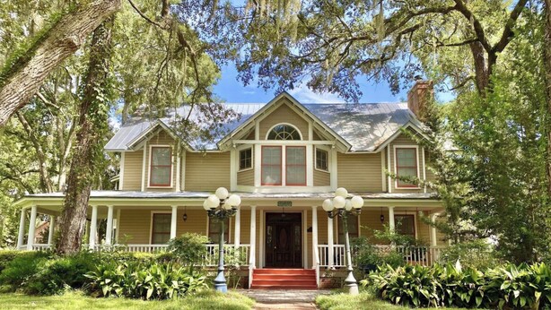 A two-story house with a front porch, columns, and a red door.