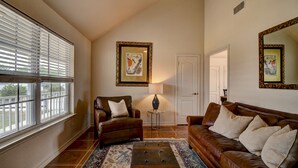 A living room with a brown leather sofa, a matching armchair, a coffee table, and a patterned rug. There is a framed picture on the wall and a lamp on a side table. - Cottage House, 3BR/2BA, Sleeps 8, Porch, Grill, Firepit (Kerr County)