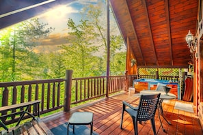 Una terraza de madera con vista a árboles, un jacuzzi y mobiliario exterior.