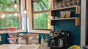 Eine Küche mit Kaffeemaschine, Spüle und einem Fenster mit Blick auf Bäume.