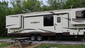 A large RV with a slide-out shower and a picnic table in front. - Luxury 5th Wheel Glamping In Style In Historic Mentone,  Alabama (Mentone)