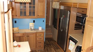 A compact kitchen with wooden cabinets, a stainless steel refrigerator, a microwave, and a coffee maker. - Luxury 5th Wheel Glamping In Style In Historic Mentone,  Alabama (Mentone)