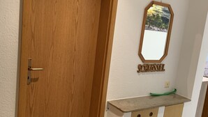 Uma porta de madeira com um respiradouro, um espelho pequeno na parede e um armário com bancada.