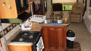 A compact kitchen with a stove, sink, and microwave.