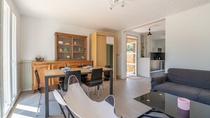A modern living room with a glass coffee table, a sofa, and a dining area with a wooden table and chairs.