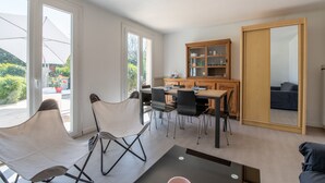 A modern living room with a dining area, a kitchen, and a sliding door leading to a balcony.