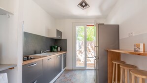 A compact kitchen with grey cabinets, a wooden countertop, and a patterned floor.
