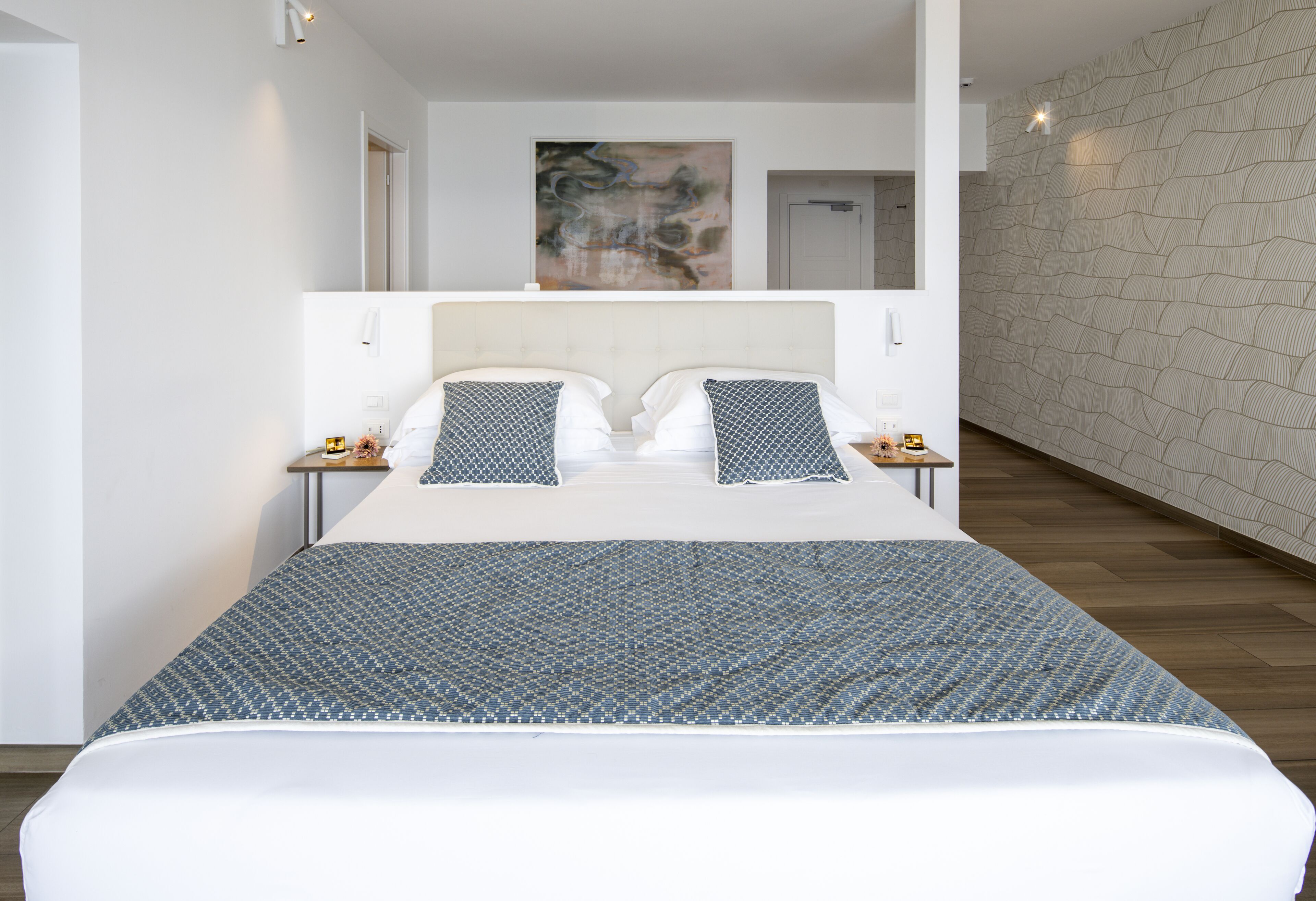 A modern bedroom with a large bed, two nightstands, and a textured wall.