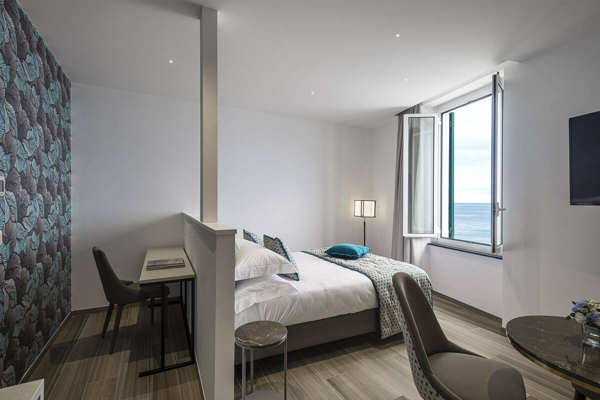 Een moderne slaapkamer met een bed, nachtkastje, stoel en een raam met uitzicht.