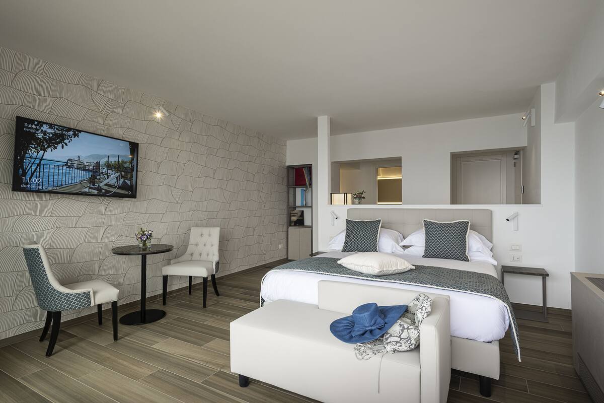 Een moderne hotelkamer met een groot bed, een bank, een klein rond tafeltje en een aan de muur bevestigde televisie.