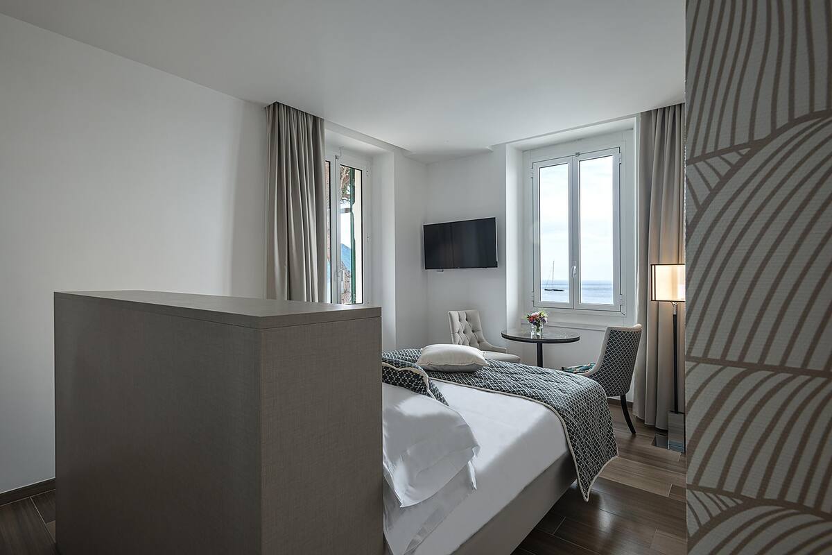 Een hotelkamer met een bed, een stoel, een televisie en een raam.