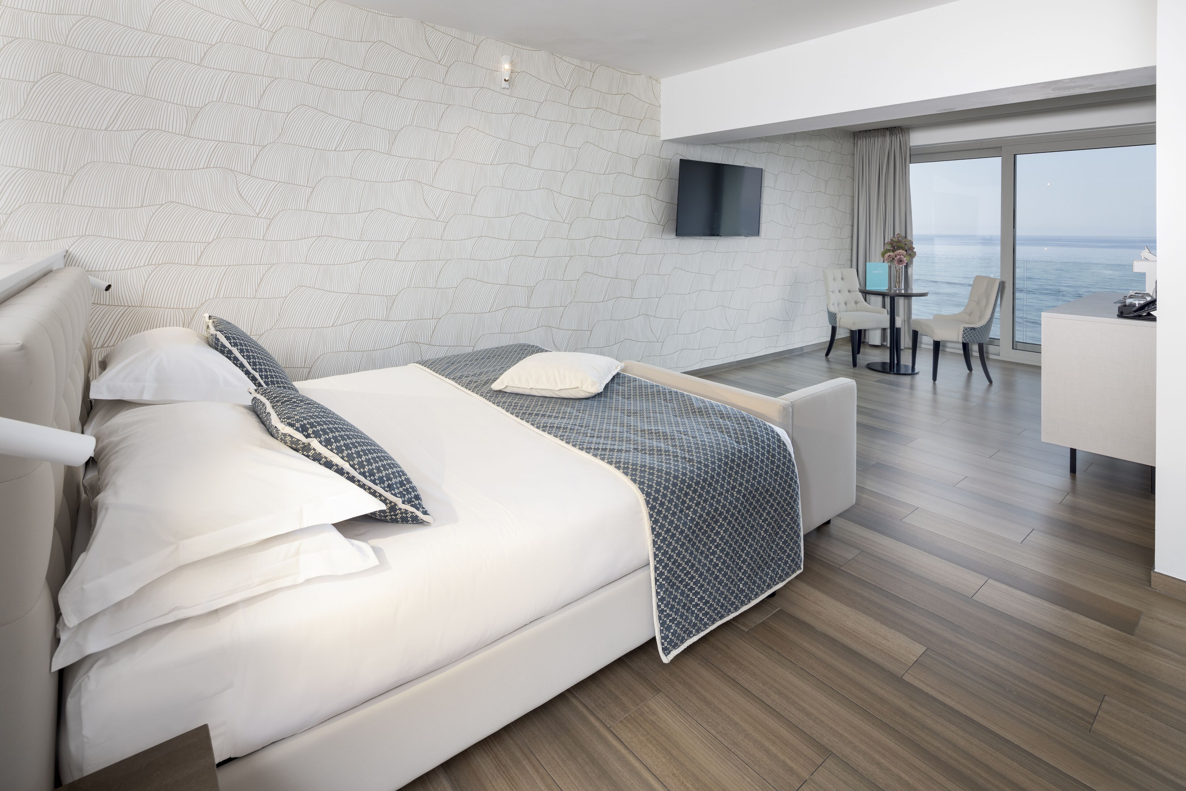 Une chambre d’hôtel moderne avec un grand lit, un bureau et une vue sur la mer.