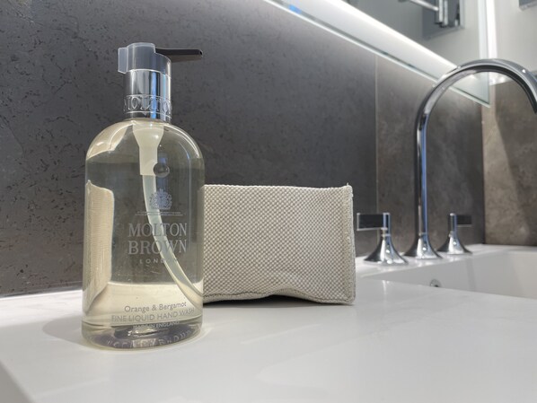 A bathroom with a clear bottle of Molton Brown hand wash, a towel, and a modern faucet. - Sublimis Boutique Hotel, WorldHotels Elite (Camogli)