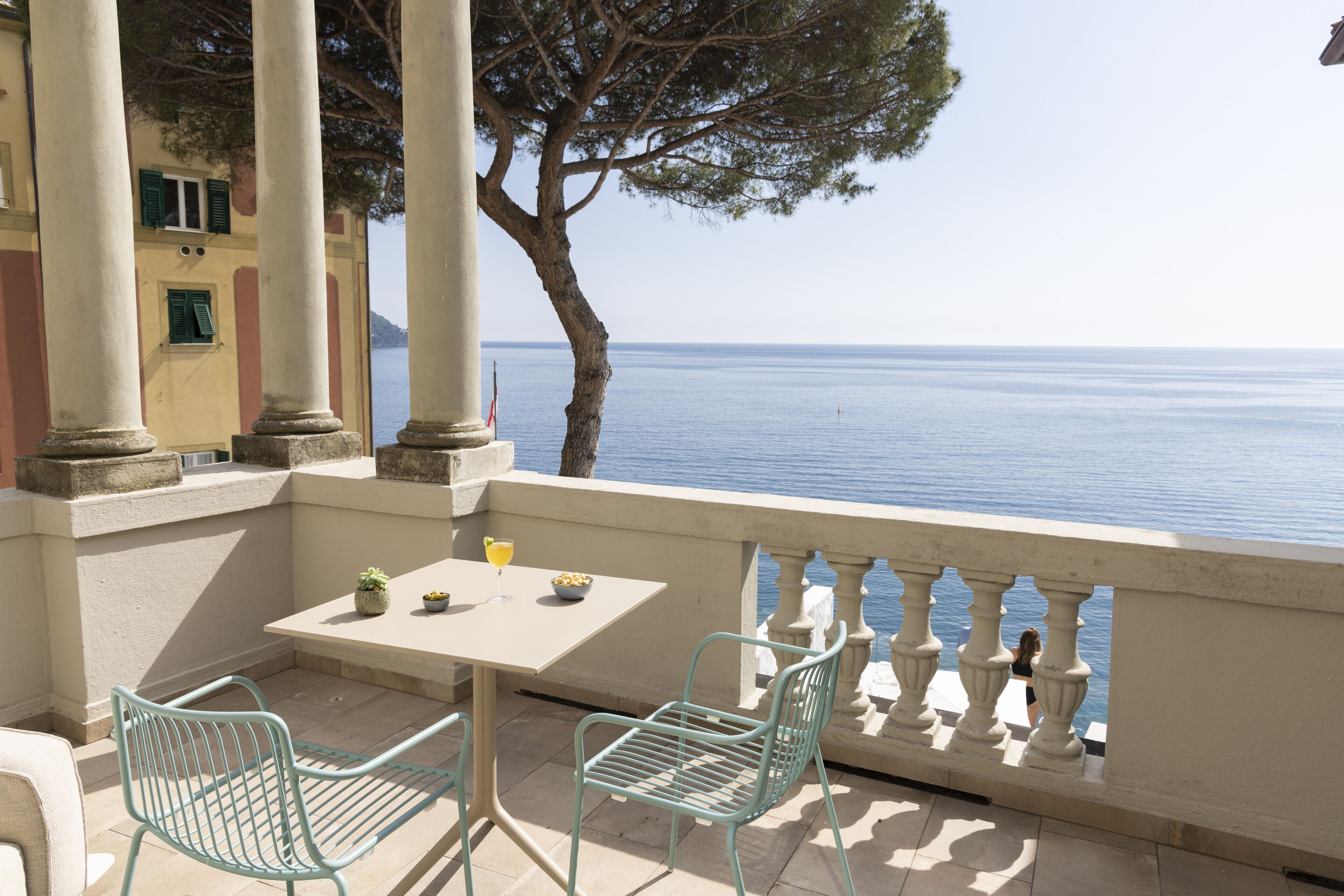 A balcony with a table and chairs, overlooking a body of water.