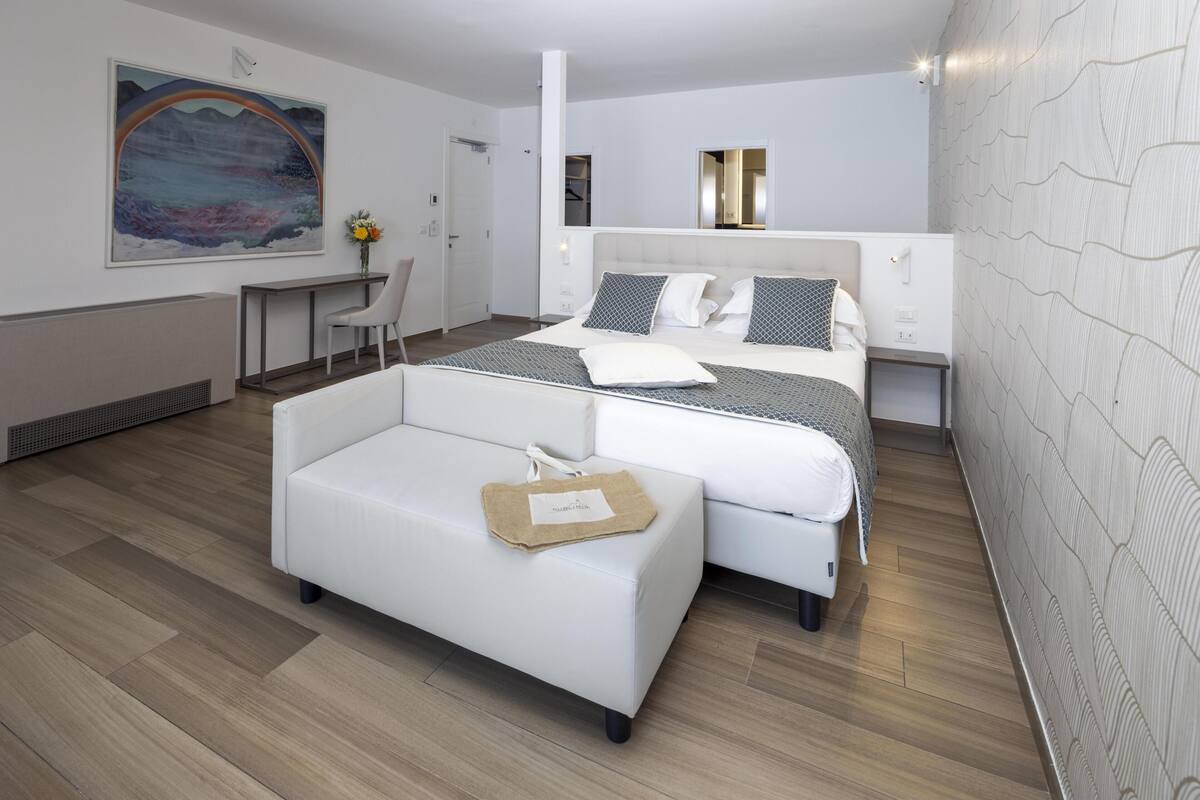 Een moderne hotelkamer met een bed, een bank, een bureau en een groot schilderij aan de muur.