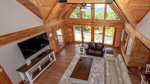 A spacious living room with a large TV, leather sofas, and a wooden ceiling. - This 5 bedroom 5 bath log cabin with spectacular views, secluded, & Hot-tub (Townsend)