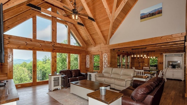 A spacious living room with a high ceiling, large windows, and a view of the outdoors. - This 5 bedroom 5 bath log cabin with spectacular views, secluded, & Hot-tub (Townsend)