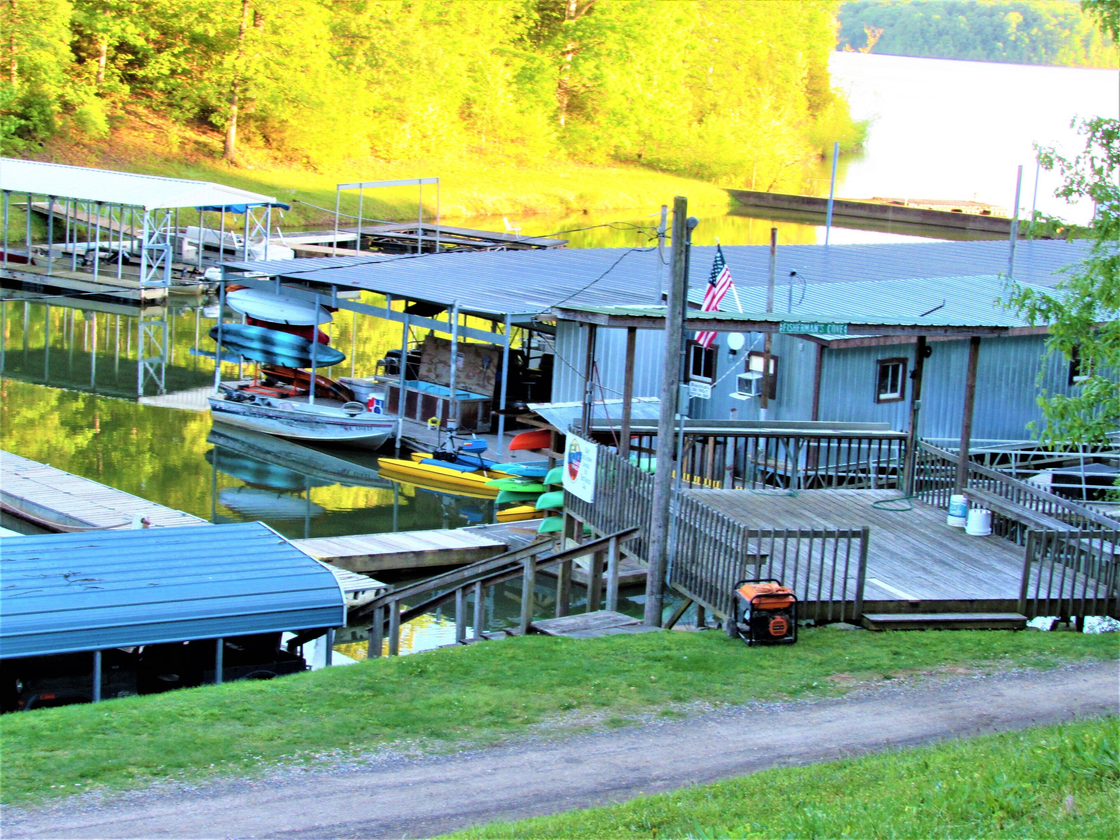 A dock with boats, a wooden building with an American flag, and a grassy area.