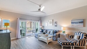Ein Wohnzimmer mit einer Couch, Sesseln, einem Couchtisch und einem Deckenventilator.
