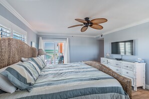 Een slaapkamer met een bed, een plafondventilator, een televisie en een balkon.