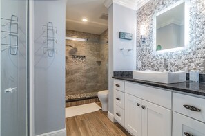 Een moderne badkamer met douche, toilet en wastafel.