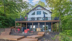 Une maison à deux étages dotée d’une terrasse, d’un espace salon extérieur et d’une grande fenêtre.