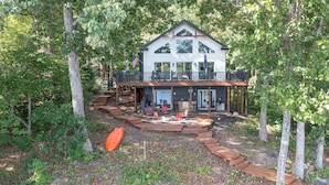 Une maison à deux étages avec un balcon, entourée d’arbres.