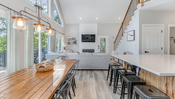 Une cuisine moderne avec une table à manger en bois, des tabourets de bar et un grand îlot central.