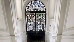 A black wrought iron gate with intricate designs, set within a white arched doorway. - N&J - GLORY RIVIERA - Central - Close sea (Niza)