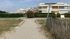 En moderne bygning med flere altaner og en sandsti, der fører til indgangen.