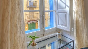 Una habitación con ventana, una mesa de vidrio, una planta en maceta y una silla.