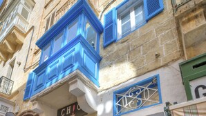 Un edificio con puerta azul y una escalera que sube a un piso superior.
