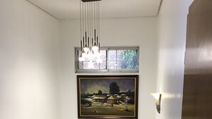 Un escalier avec une rampe, un tableau encadré au-dessus et un luminaire.