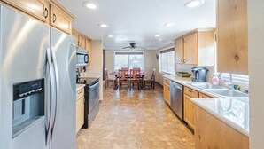 A kitchen with wooden cabinets, stainless steel appliances, a dining table with chairs, and a window with blinds. - Classy, Clean & Comfortable - Close to Downtown (Kanab)