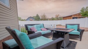 An outdoor patio area with wicker furniture, including a sofa and chairs, and a table with a fire pit. - Classy, Clean & Comfortable - Close to Downtown (Kanab)