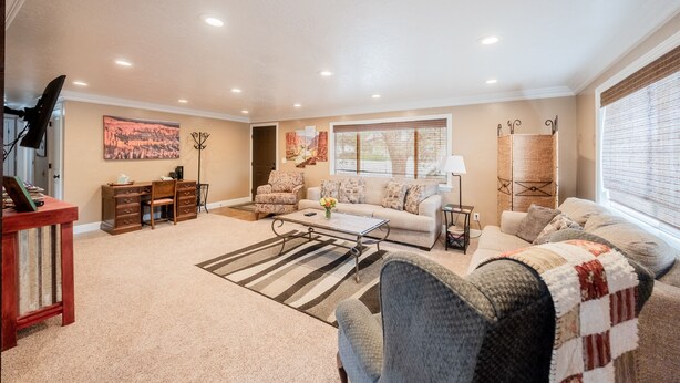 A spacious living room with a sofa, coffee table, and a TV stand. - Classy, Clean & Comfortable - Close to Downtown (Kanab)